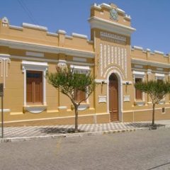 Fachada de um prédio histórico em Piratini, com paredes amarelas e detalhes arquitetônicos.